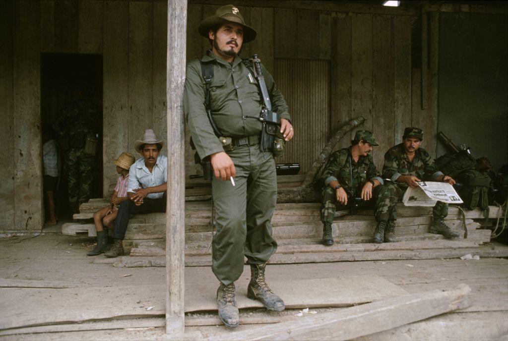 Photo of Contra commander "Franklin" leaning against a support beam with two of his soldiers sitting behind him circa 1990.